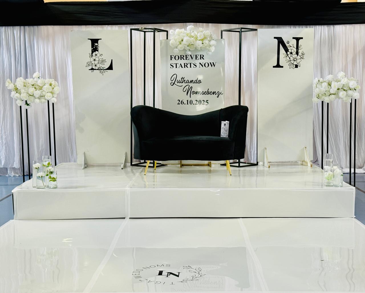 Monogram backdrop with black velvet couch on white stage
