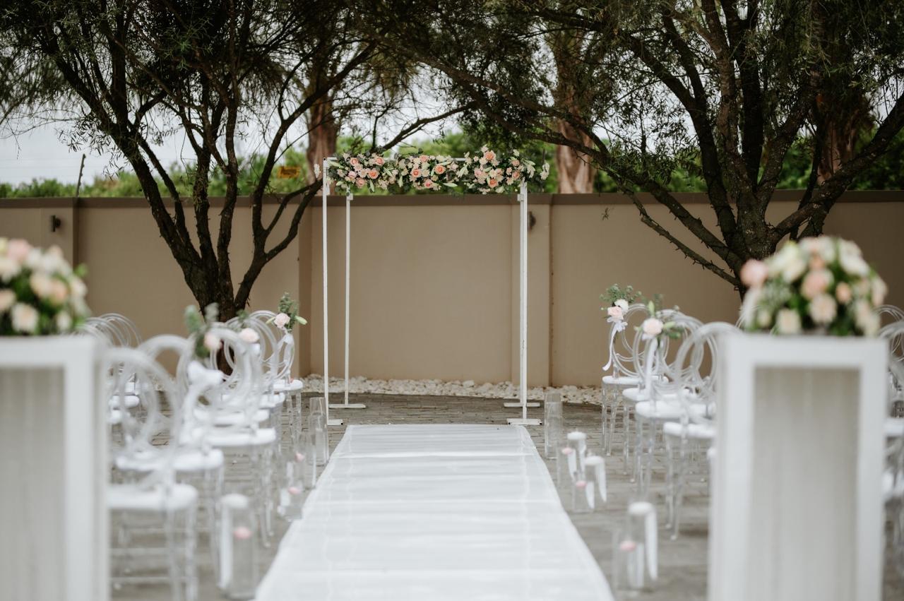 Outdoor wedding aisle with floral arch and clear phoenix chairs