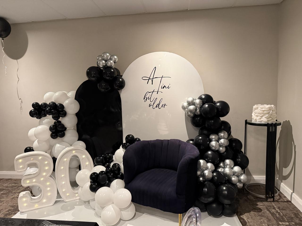 30th birthday balloon arch with marquee '30' letters and velvet chair